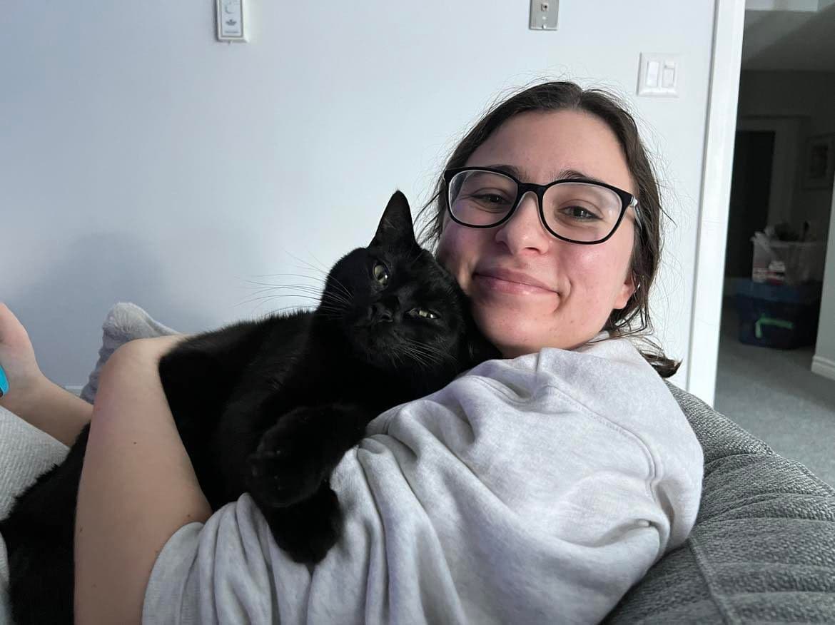 A cute black cat cuddling his owner