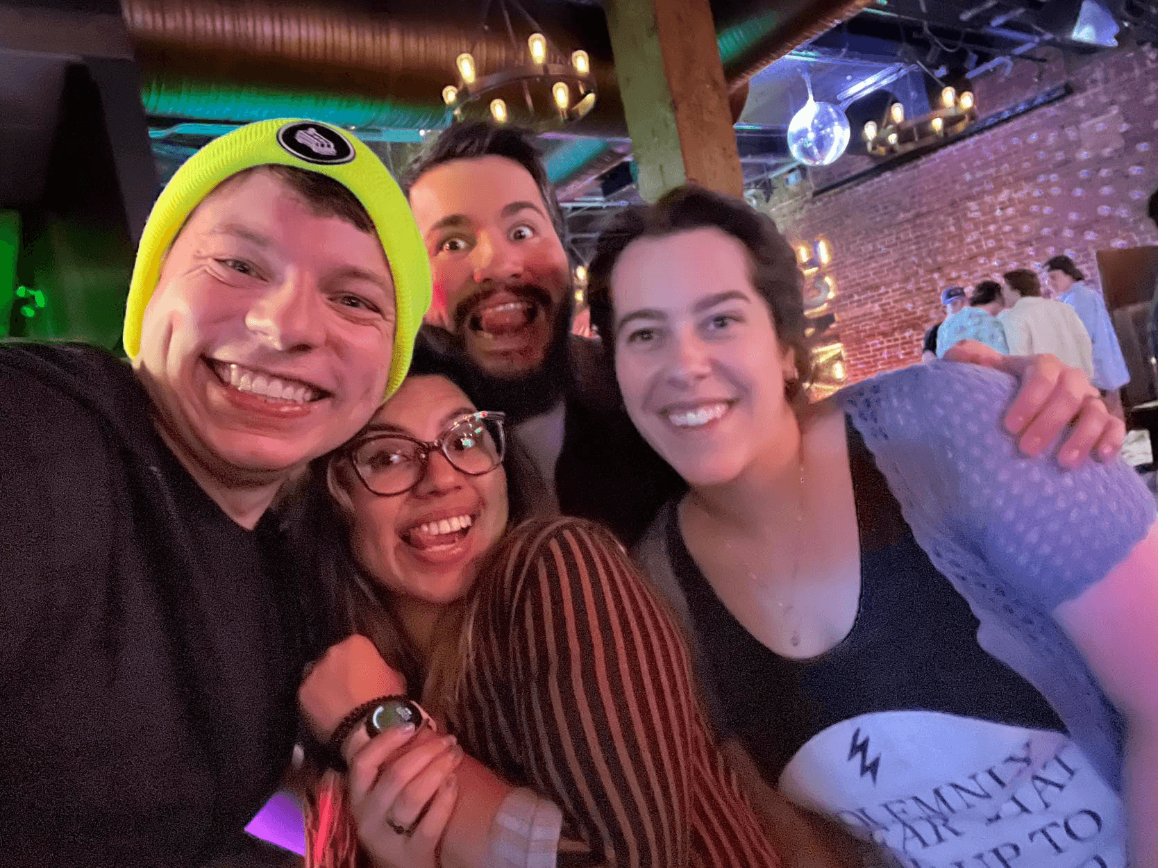 4 friends outside a bar, one wearing a very bright yellow hat