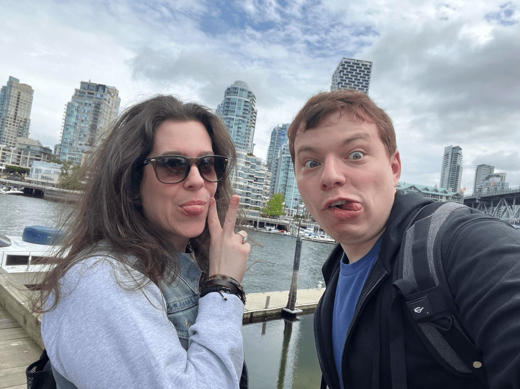 2 friends on a pier sticking out their tongues at the camera