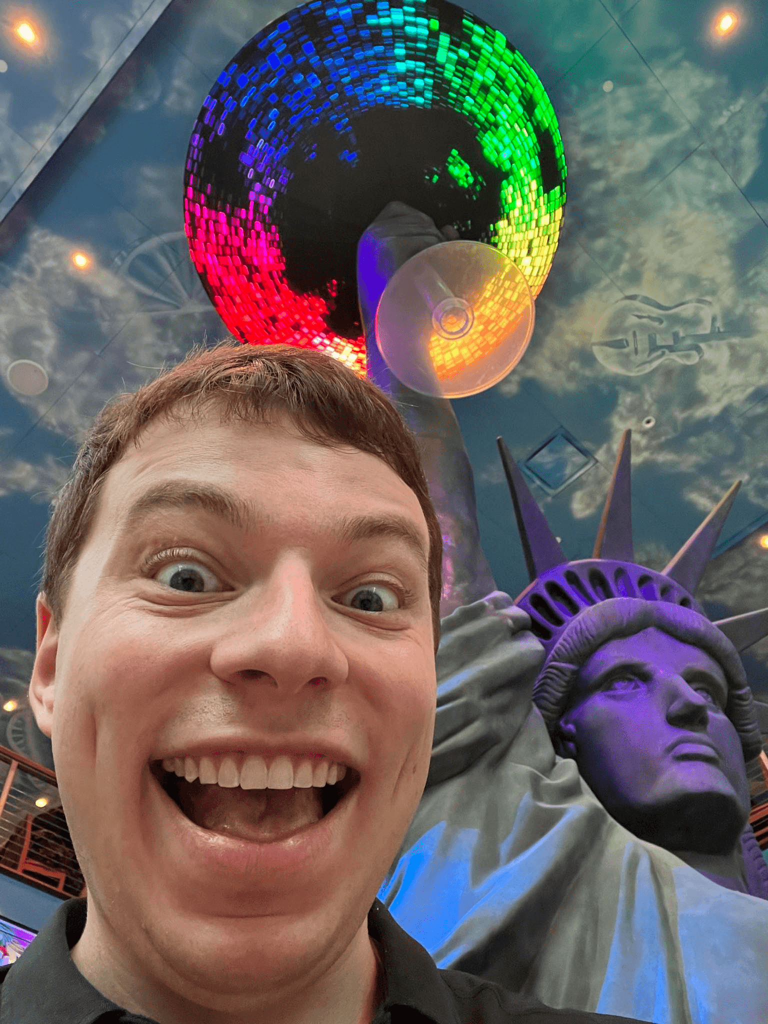 A guy in front of a statue of liberty holding a Margarita