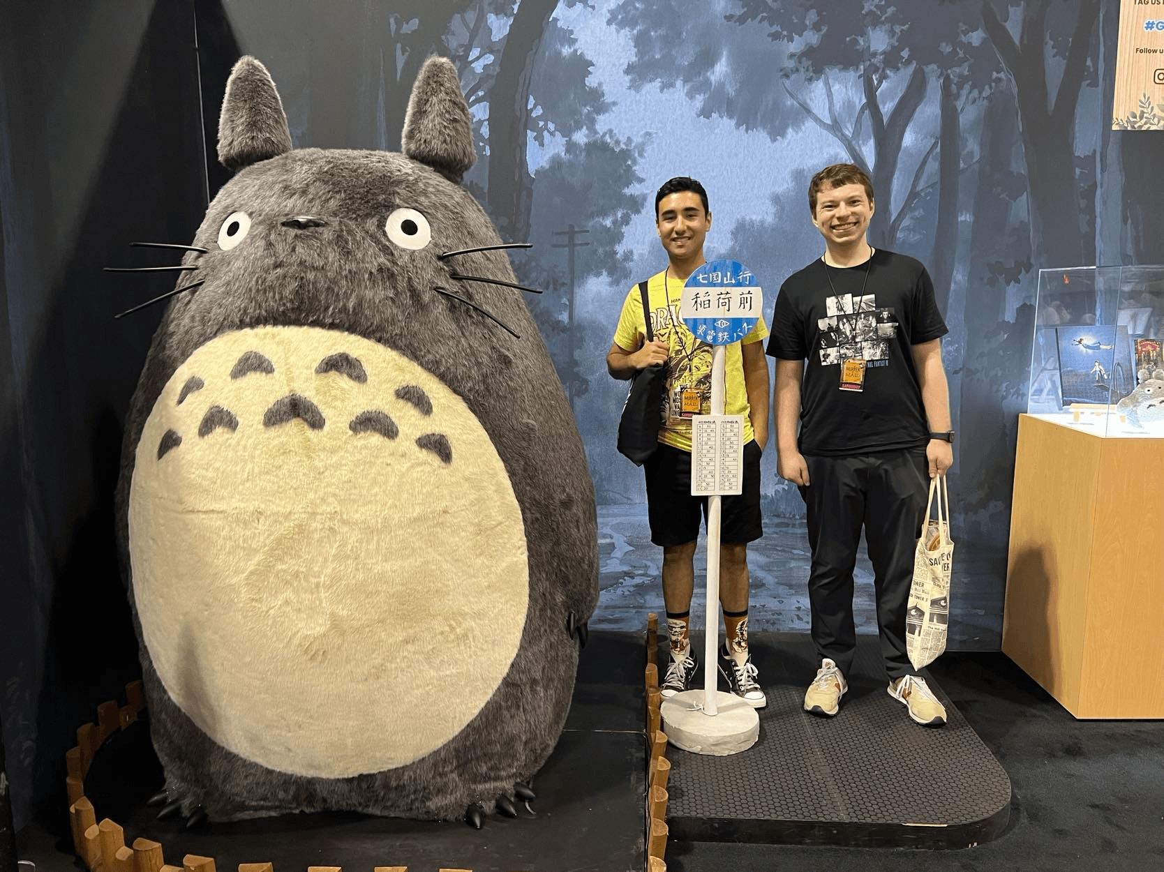 Two guys standing beside Totoro