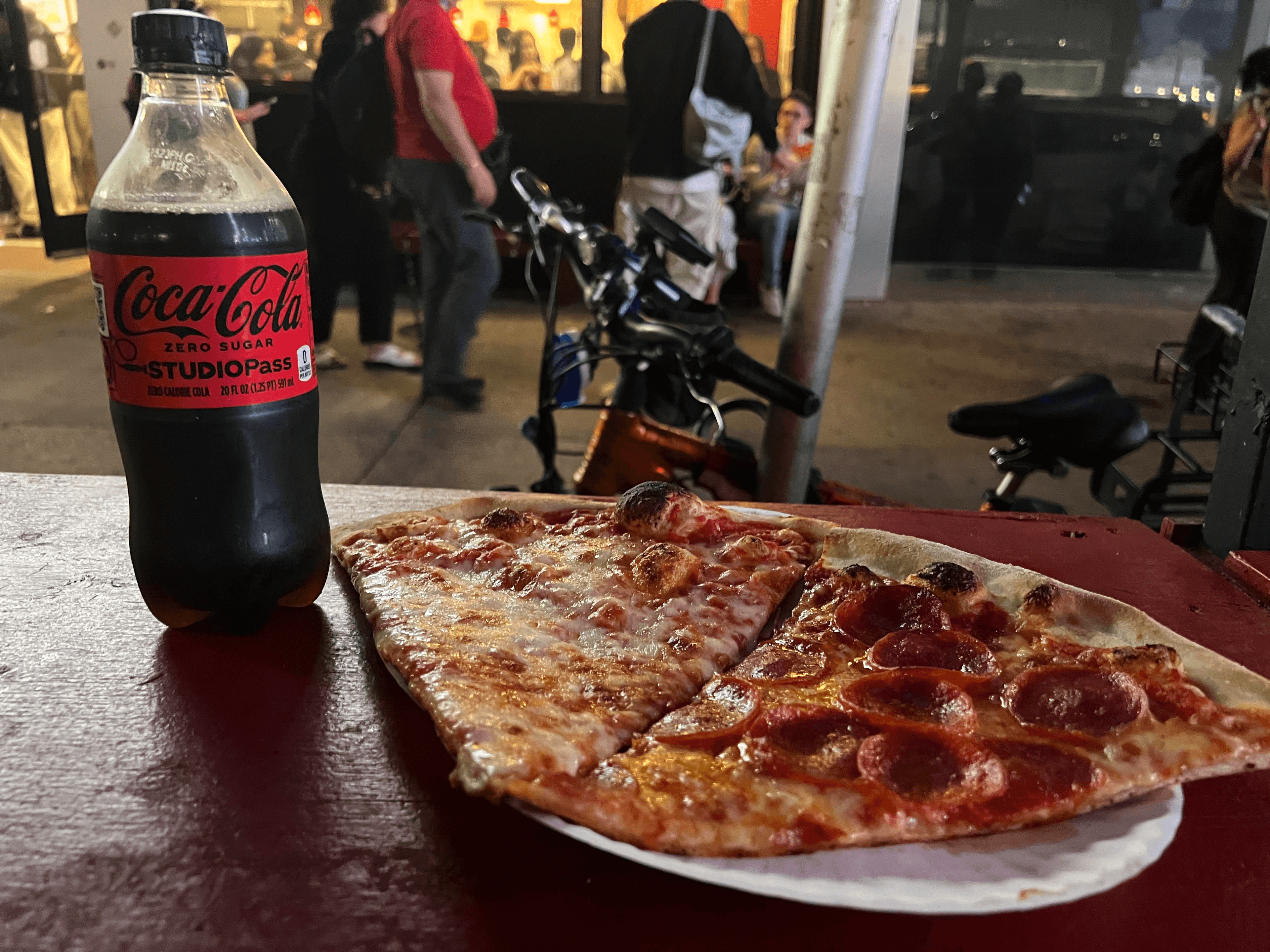 2 Pieces of Joe's Pizza beside a bottle of Coke Zero