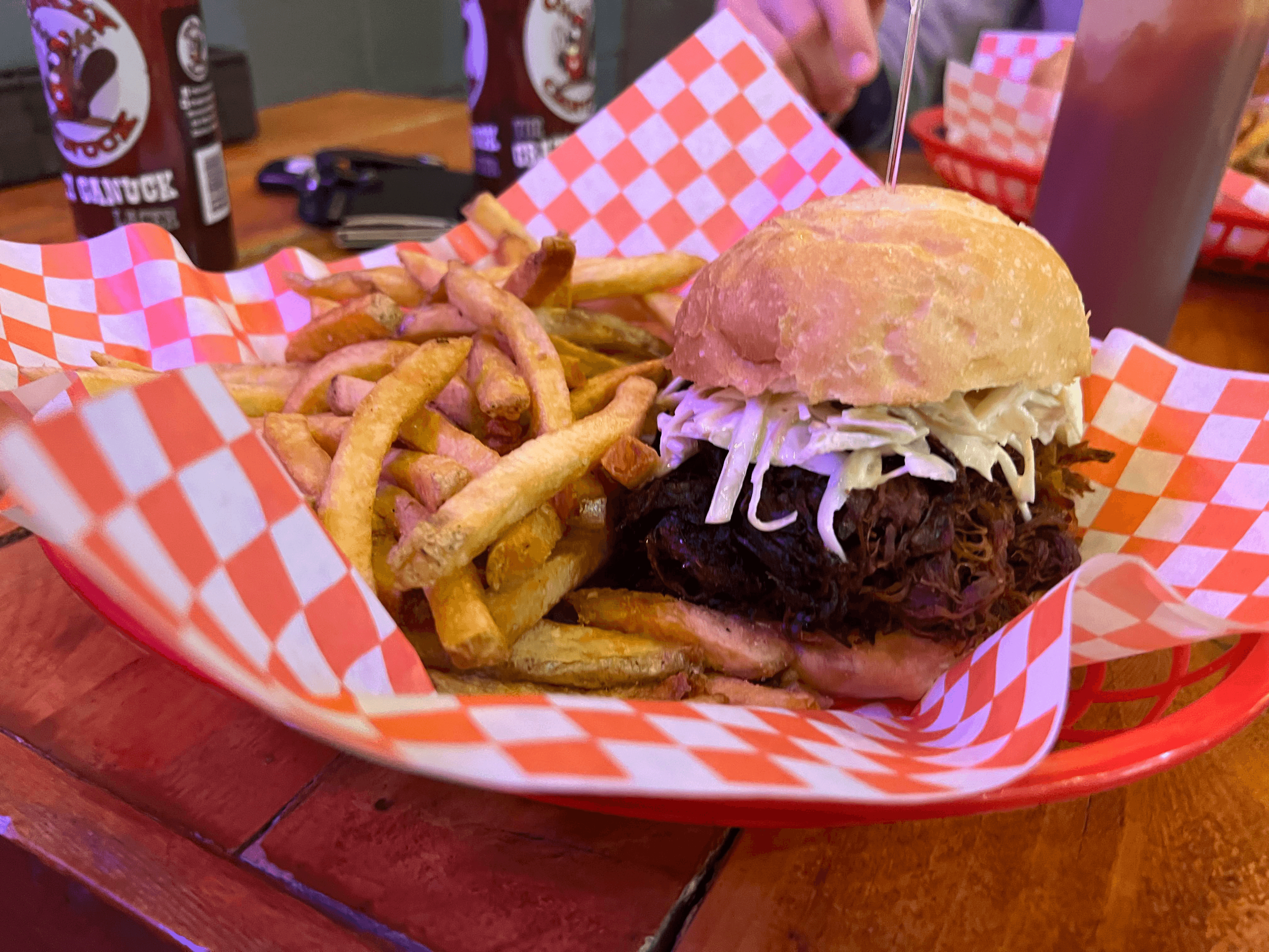 A pulled pork sandwich beside some fries